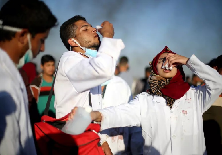 Nurse Razan Al-Najar reacts to tear gas as she works at the scene of clashes at Israel-Gaza border (photo credit: IBRAHEEM ABU MUSTAFA / REUTERS)